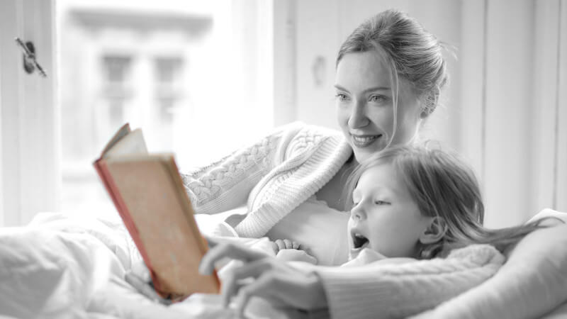 un enfant qui lit un livre avec sa maman