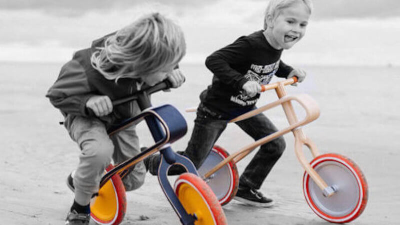 dos niños con una bicicleta de equilibrio de madera